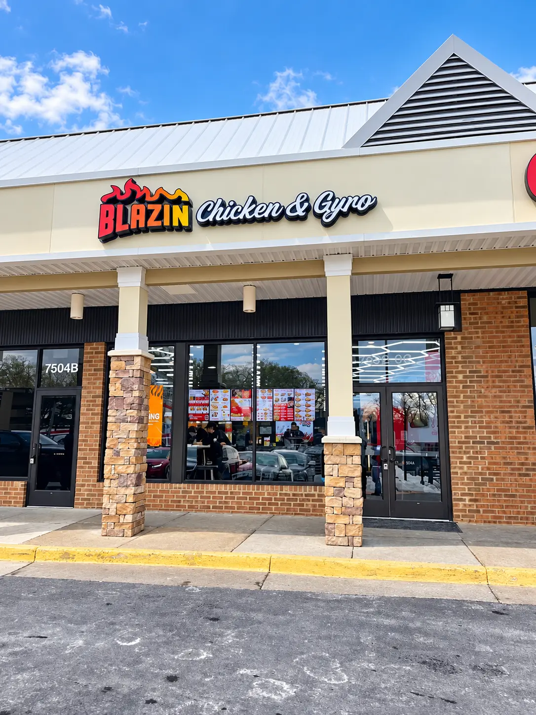 Blazin Chicken & Gyro storefront on Leesburg Pike near Tysons Corner in Falls Church VA, with the flame logo sign, brick and stone pillars and menu boards in the window